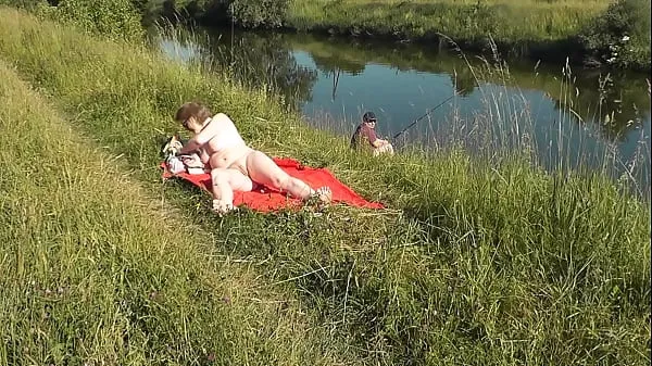 Afficher MILF sexy Frina sur la rive du fleuve se déshabille et prend un bain de soleil nue. Un pêcheur au hasard la surveillait et a finalement décidé de rejoindre une femme nue. Plage sauvage. Plage de nudistes. Nudité publique vidéos Drive